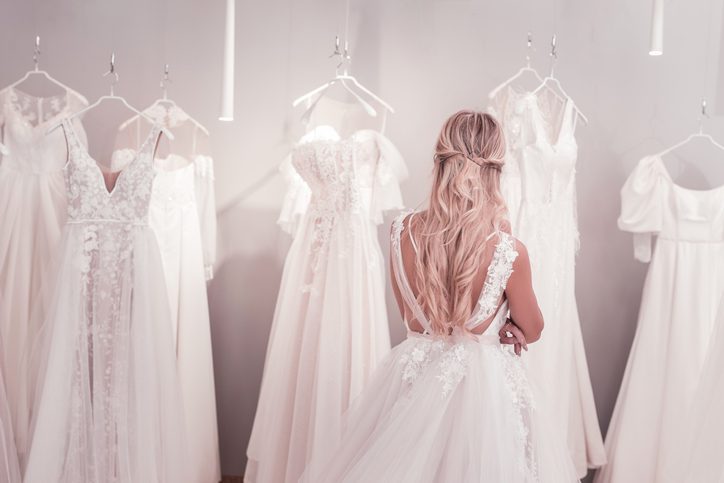 Beautiful blonde woman standing in front of wedding dresses