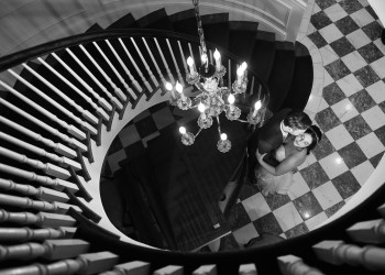 a black and white photo of a bride and groom at the bottom of a spiral staircase