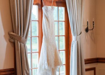 a wedding dress, hanging up infront of a windpw