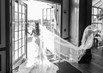 a black and white photo of a bride, walking outside