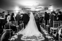 a black and white photo of a bride walking down the alter