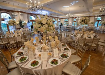 a wedding reception area with tables set up, with food, glasses, and floral centerpieces