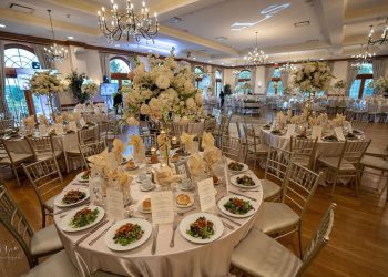 a wedding reception area with tables set up, with food, glasses, and floral centerpieces