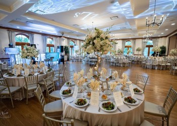 a wedding reception area with tables set up, with food, glasses, and floral centerpieces