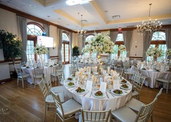a wedding reception area with tables set up, with food, glasses, and floral centerpieces