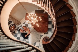 a bride and groom at the bottom of a spiral staircase