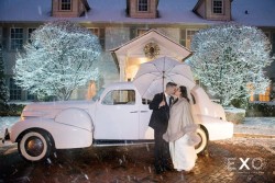 a bride and groom kissing infront of a white vehicle, in the rain