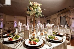 a wedding hall table, with flower centerpieces and cuisine on the table