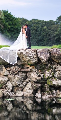 a bride and groom kissing on a rock cliff