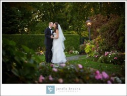 a bride and groom kissing outside, surrounded by flowers