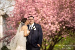a bride and groom taking a photo infront of a large tree with pink leaves
