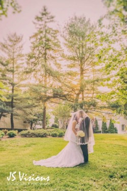 bride and groom kissing, outside surrounded by trees